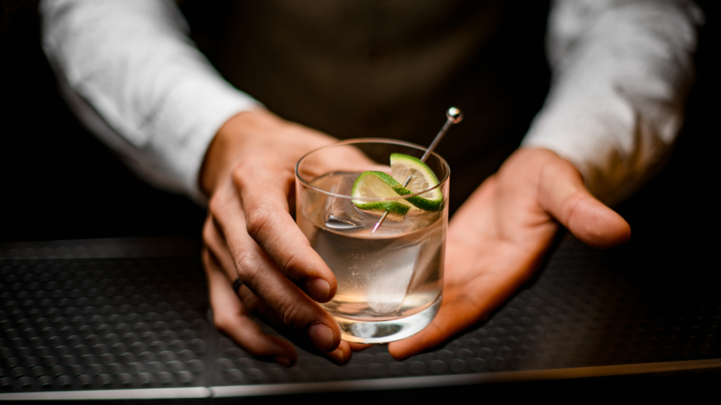 closeup on hands of man bartender holding glass with cold drink